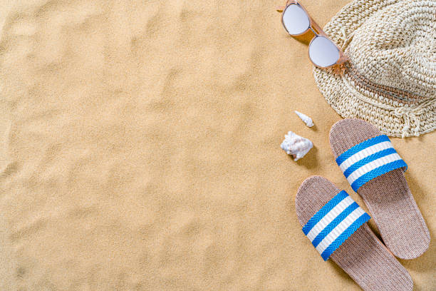 Sandals, sunglasses and sunhat on sand background