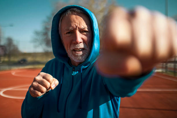 istock Serious looking senior fighter shadow boxing outdoors 1395157257