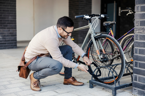 Un hombre de negocios casual encierra su bicicleta en la calle. photo