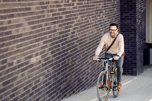 A city man riding a bicycle on the street uphill.