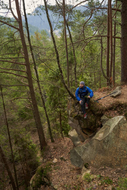 istock Male resting on rocky cliff in woods during trekking 1395160987