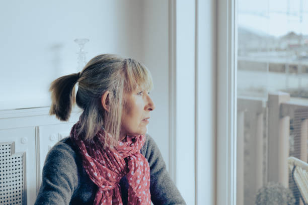Mental wellbeing can be fragile Lonely mature woman looking blankly out of the window. seasonal affective disorder stock pictures, royalty-free photos & images