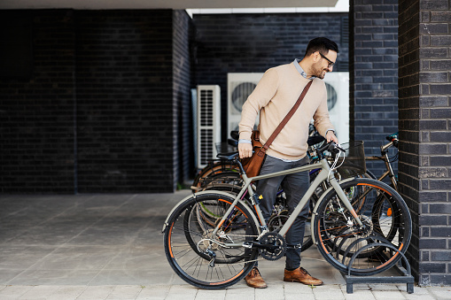 An urban man parking a bike outside.