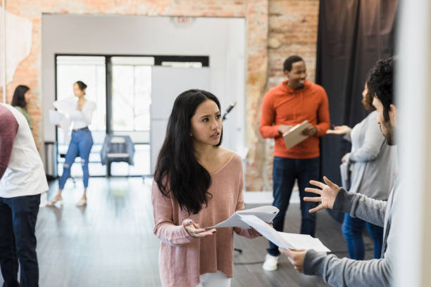 istock Young man and woman rehearse scene while others discuss script 1395164235