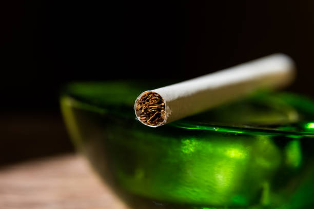 istock cigarette front view leaning on a green glass ashtray, black backgroun 1395166876