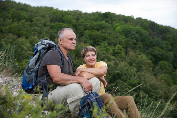 senior tourist couple sitting on the mountain. senior couple walking in nature.  travel tourism concept. outdoor activities on weekends. - couple walking old middle imagens e fotografias de stock