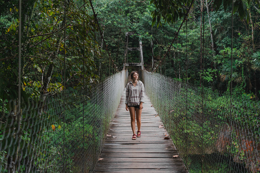 Woman walking on suspension bridge over  Las Nubes waterfall in Chiapas