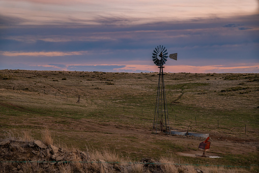 Rural ranch land windmill at sunset in central Montana in northwestern United States of America (USA). Nearest cities are Bozeman, Great Falls, Billings, Montana.