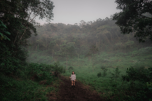 Young Caucasian woman  hiking  in the jungles in fog