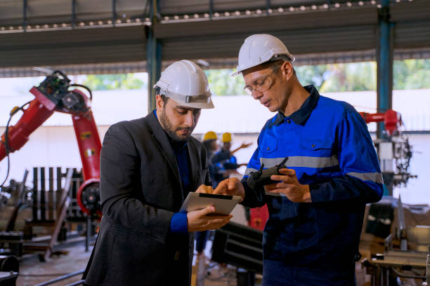istock Employees are working at factory with robotic arms. 1395174107