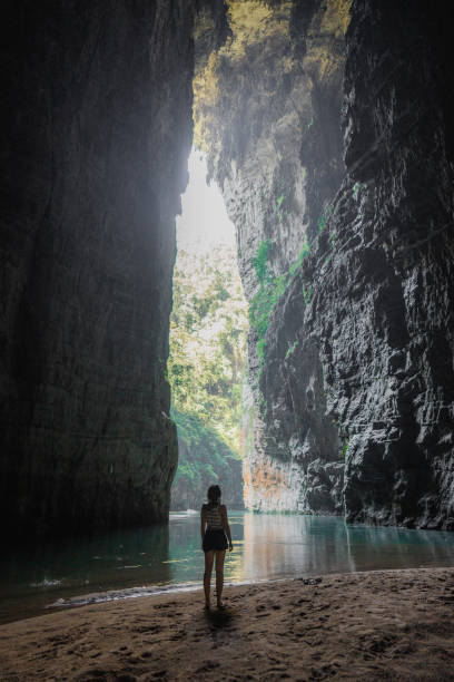 donna in piedi nella grotta arc del tiempo vicino al fiume turqouise in chiapas, messico - women rear view one person arch foto e immagini stock