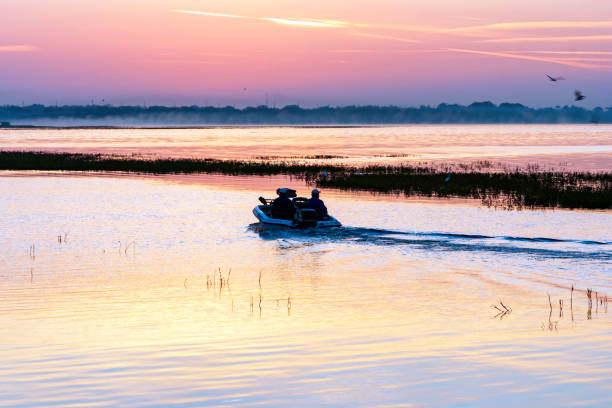 Silhouette of two fishermen leaving Kissimmee Marina in their Bass Boat for an early morning fishing adventure out on Lake Toho  in central Florida stock photo