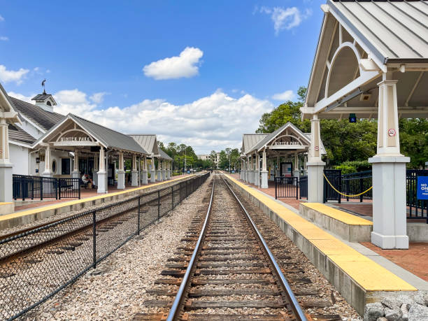 These commuter rail station platforms, which also serve interstate rail travelers, are located on a double tracked rail line next to a beautiful urban park in Winter Park, Florida. These commuter rail station platforms, which also serve interstate rail travelers, are located on a double tracked rail line next to a beautiful urban park in Winter Park, Florida. winter park florida stock pictures, royalty-free photos & images