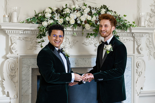 A mid-length view of two male grooms exchanging vows and looking to the people with them in a registry office in Durham in the North East of England