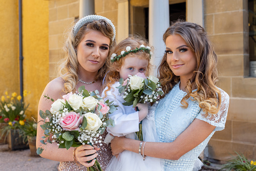 A close-up portrait of three bridesmaids looking into the camera after attending a wedding of family members in County Durham in the North East of England.