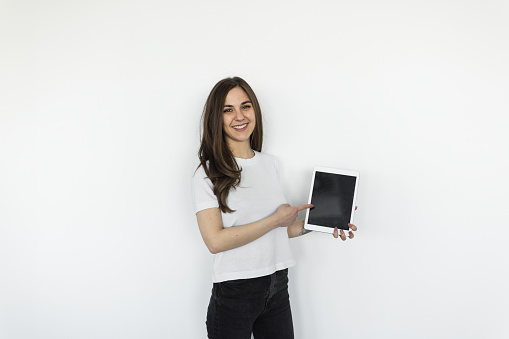 Young woman pointing on a tablet on a white background