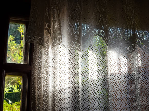 Sunlight entering the room through  white lace curtains