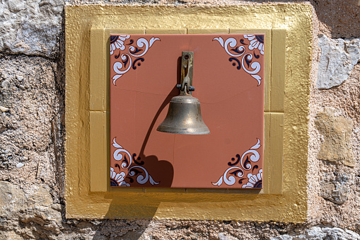 Small bell on a tile decorated with drawings
