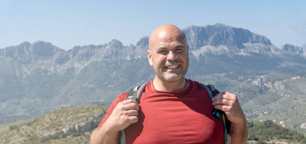 istock male hiker smiling with mountains in the background. 1395182491