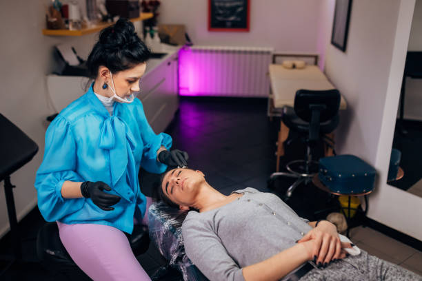 istock The beautician wears protective black gloves and a protective visor while doing permanent eyebrow pigmentation to the customer 1395183427