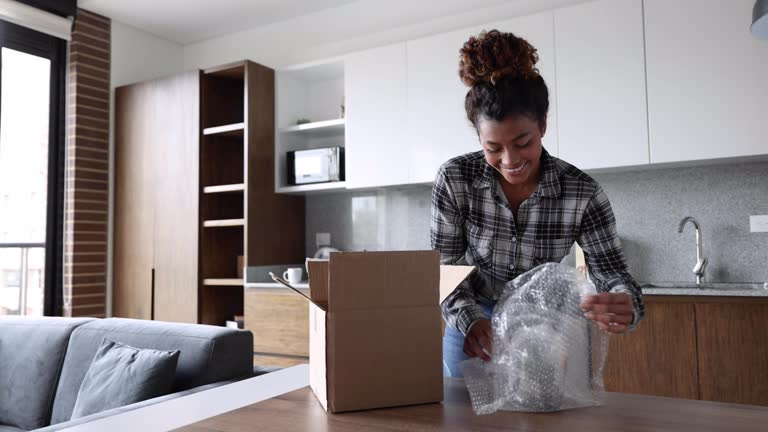 Happy young woman opening a package she received at home after shopping online