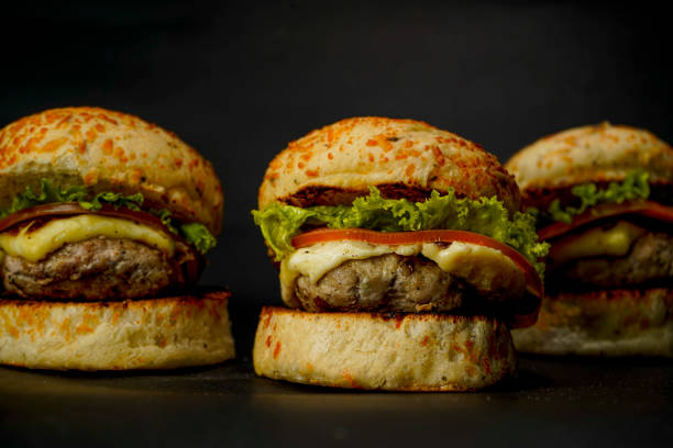 istock Three mini burgers on black background 1395187888