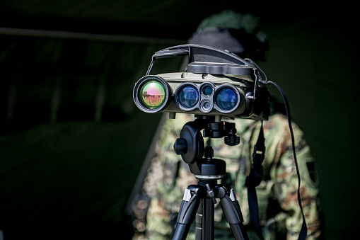 Army soldier looking through professional surveillance binoculars.