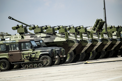 Military armored tank moving at a high rate of speed with motion blur over sand. Generic photo realistic 3d model scene.