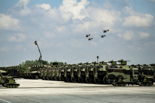 Large group of army vehicles and aircraft in a military base.