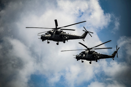 Silhouettes of khaki helicopters with red stars on background of cloudy gray clouds. Four helicopters are flying in battle formation in dark stormy sky.