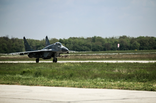 Military figher airplane landing on an airport runway.