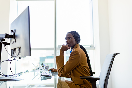 Black female CEO working in her modern office. She is using desktop computer
