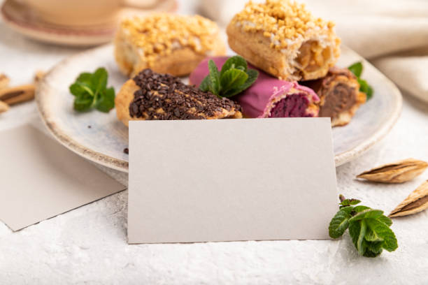 Gray paper business card and set of eclair on gray concrete background. side view side view, close up.