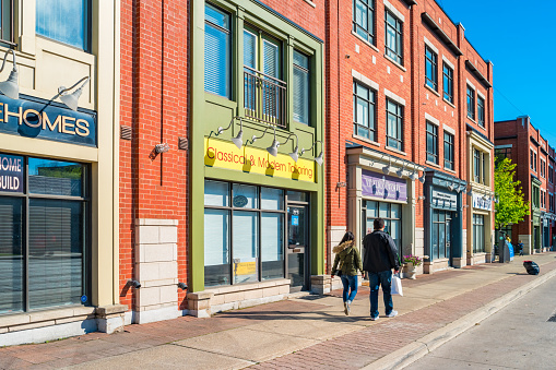 Couple walks past colorful stores in Port Credit Mississauga Ontario Canada on a sunny day.