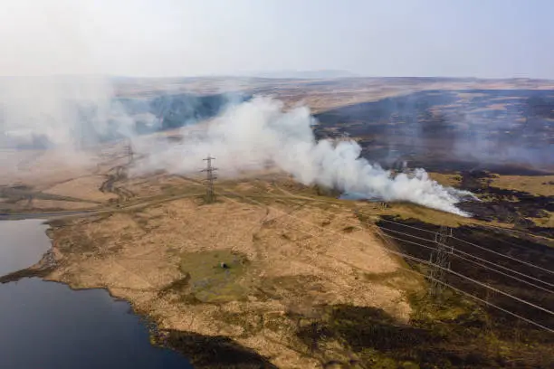Aerial view of smoke and flames from a large grassfire on moorland in South Wales, UK (Llangynidr Moors, Wales)