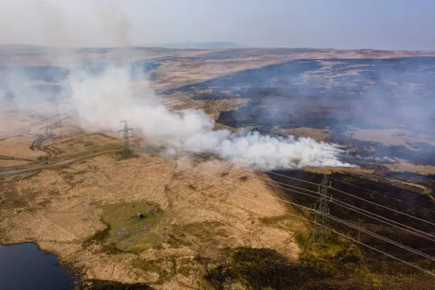 Aerial view of smoke and flames from a large grassfire on moorland in South Wales, UK (Llangynidr Moors, Wales)