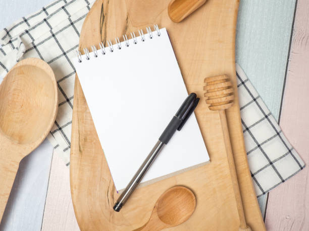 istock Notepad on cutting board with wooden kitchen utensils on the table, food recipes .copy space 1395193578