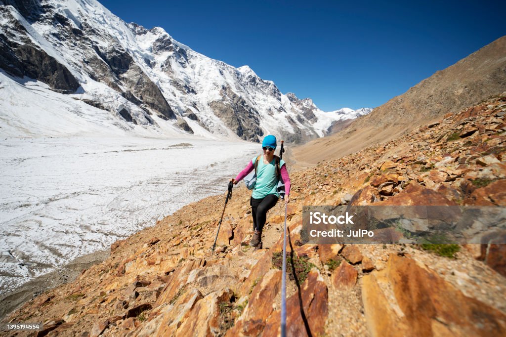 Young woman climbing with rope in mountains One young woman trekking in mountains with glacier One Woman Only Stock Photo