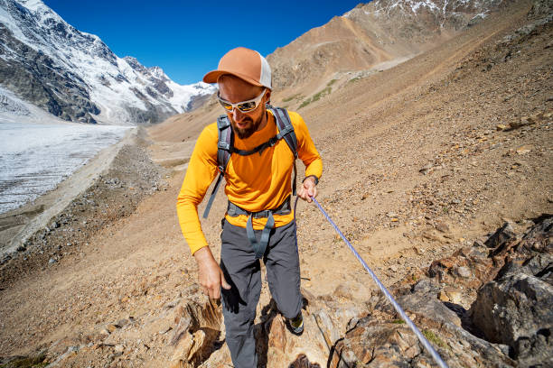 POV of backpacking woman climbing up on steep cliff edge at high altitude mountains top