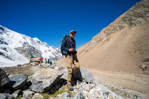 Group of tourists with photographer trekking in mountains during summer vacation