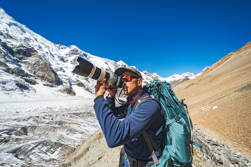 Photographer taking photos of glacier during trekking in mountains