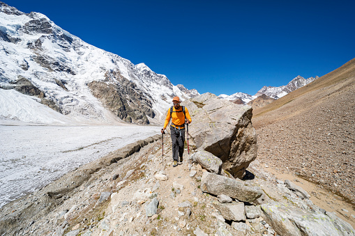 One young man trekking in mountains with glacier
