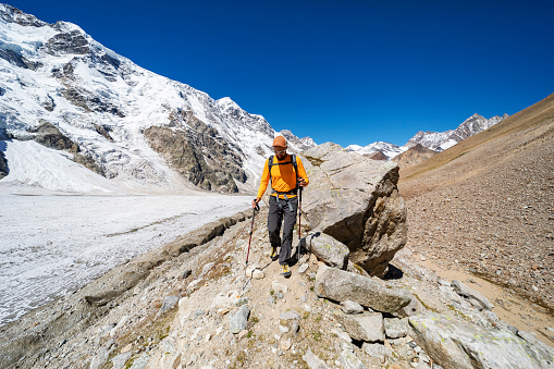 One young man trekking in mountains with glacier