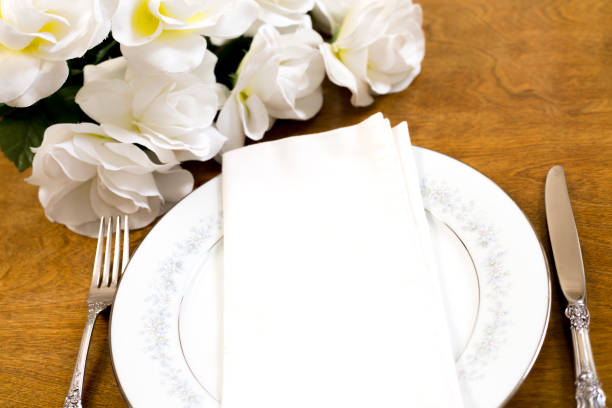 istock Place setting on table with bouquet of white roses. 1395200813