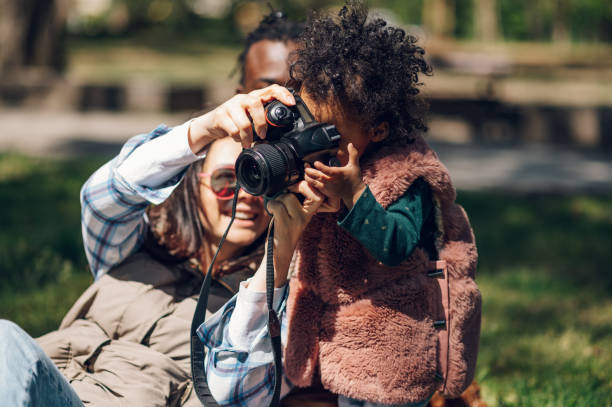 istock Beautiful multiracial family using a digital camera in the park. 1395201319