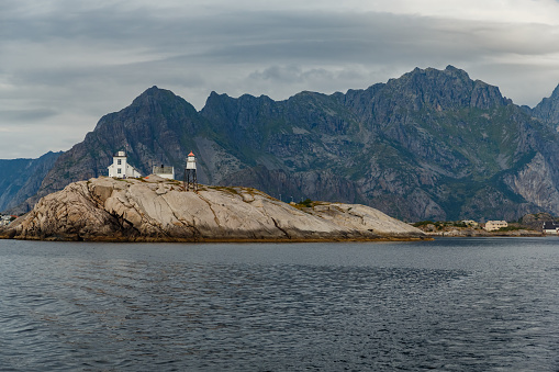 Norwegian seascape, rocky coast with dramatic skies, the sun breaks through the clouds, sheer cliffs, small islands illuminated by the sun