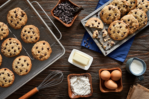Top view of homemade chocolate chips cookies and ingredients on a rustic wooden table