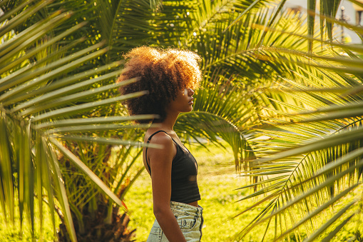 Pretty young afro woman among palm trees