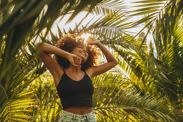 istock Pretty young afro woman among palm trees 1395212192