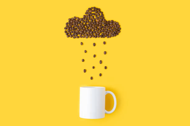 istock Shape of cloud made from roasted coffee beans is droping into white cup on yellow background. 1395212304